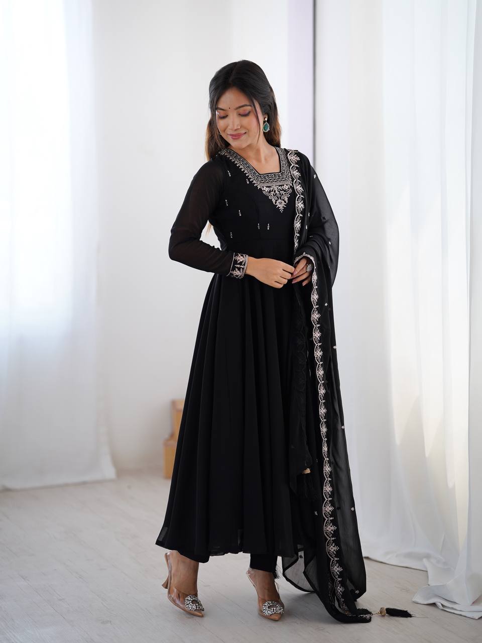 Woman wearing a black traditional outfit with silver embroidery against a white background
