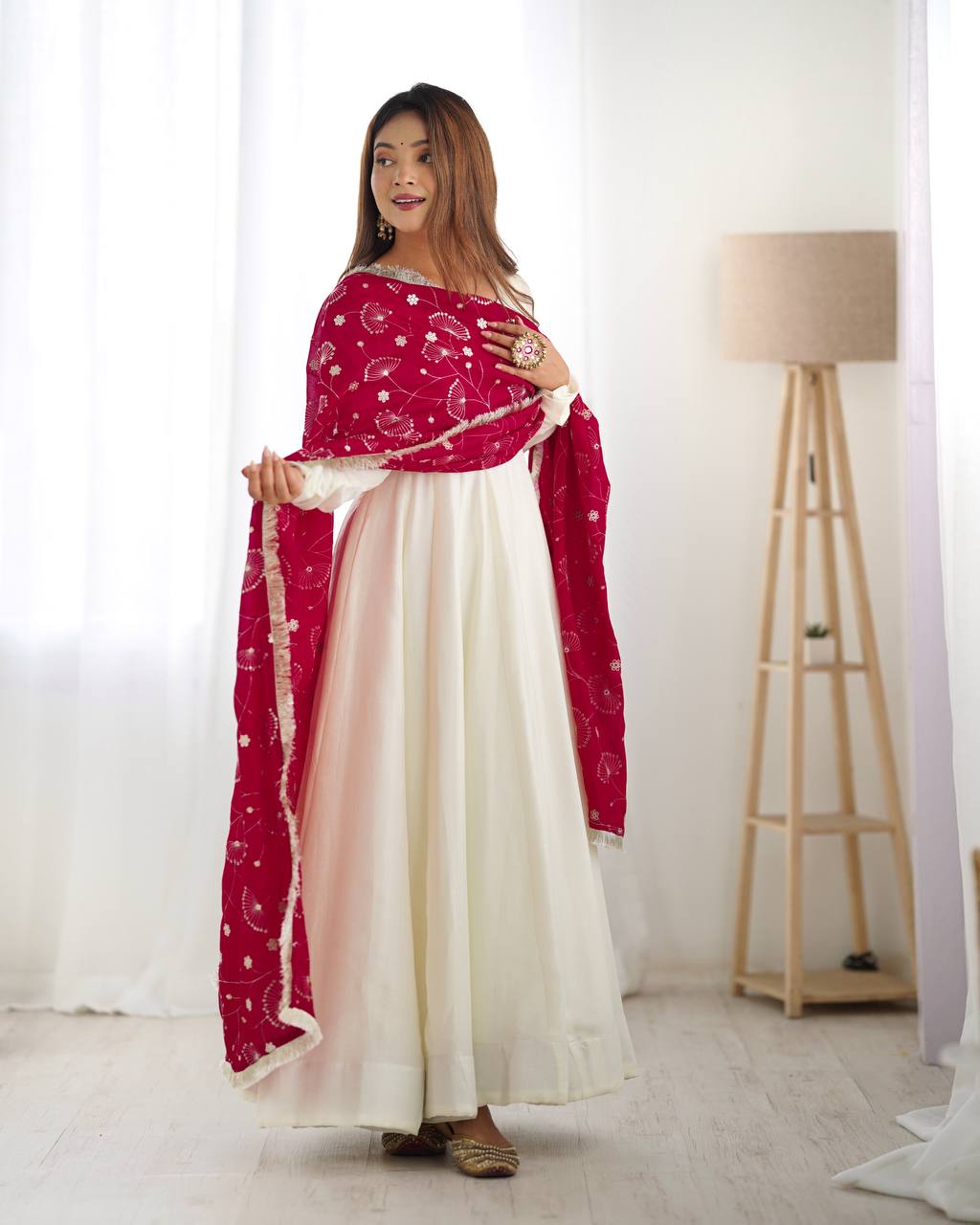 Woman wearing a red and white traditional outfit with a scarf in a bright room.