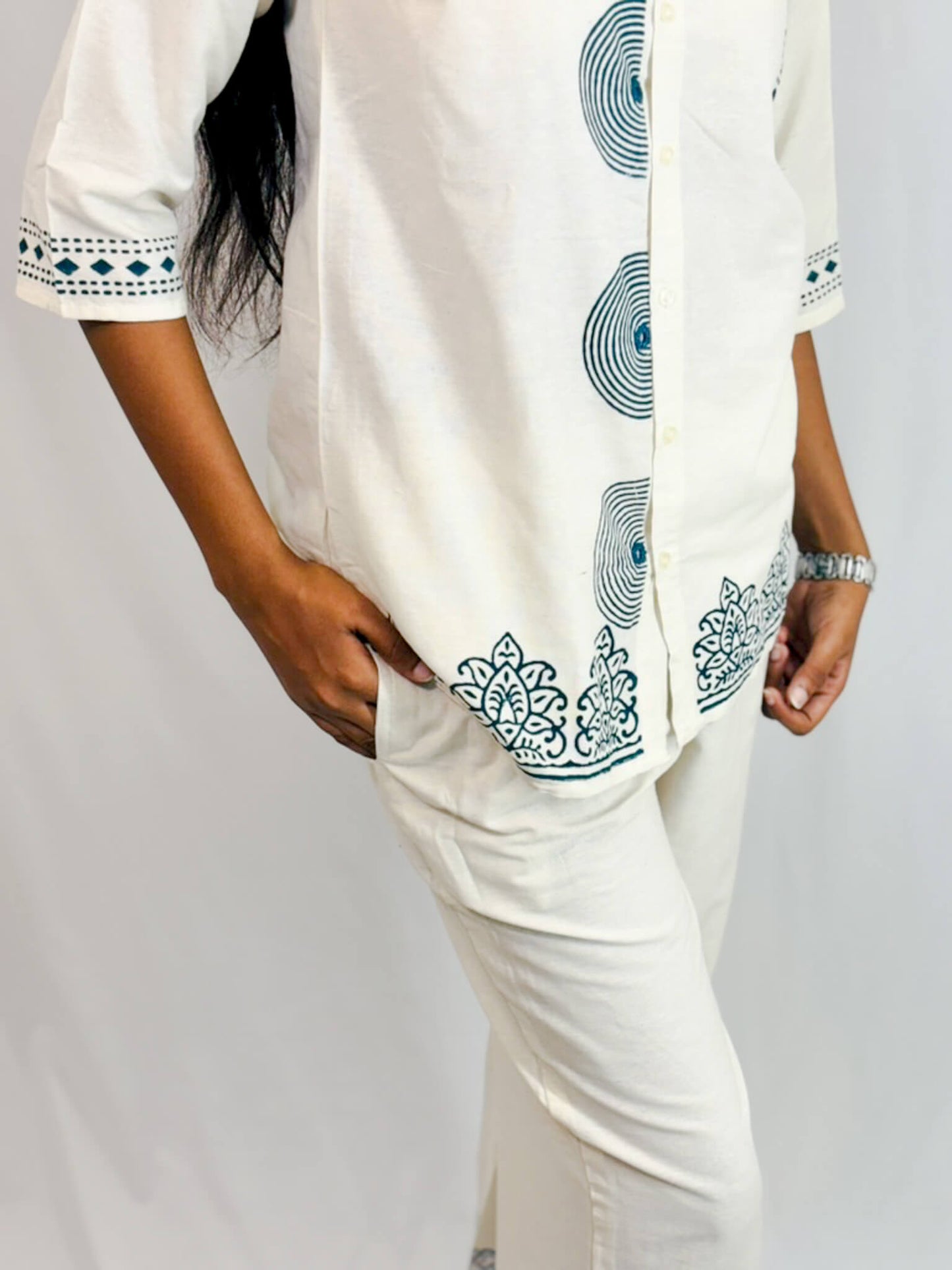 Person wearing a white outfit with green patterns on a plain background