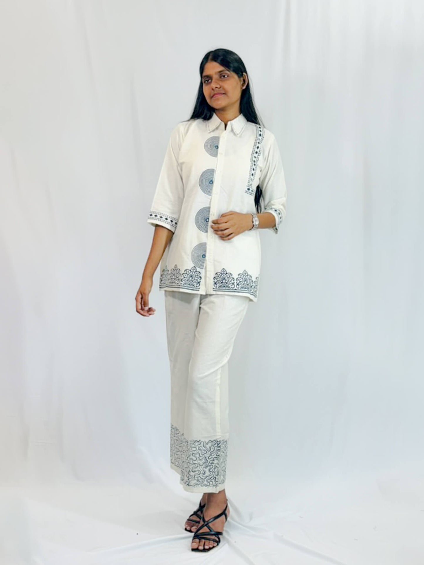 Woman wearing a white traditional outfit with black patterns on a white background