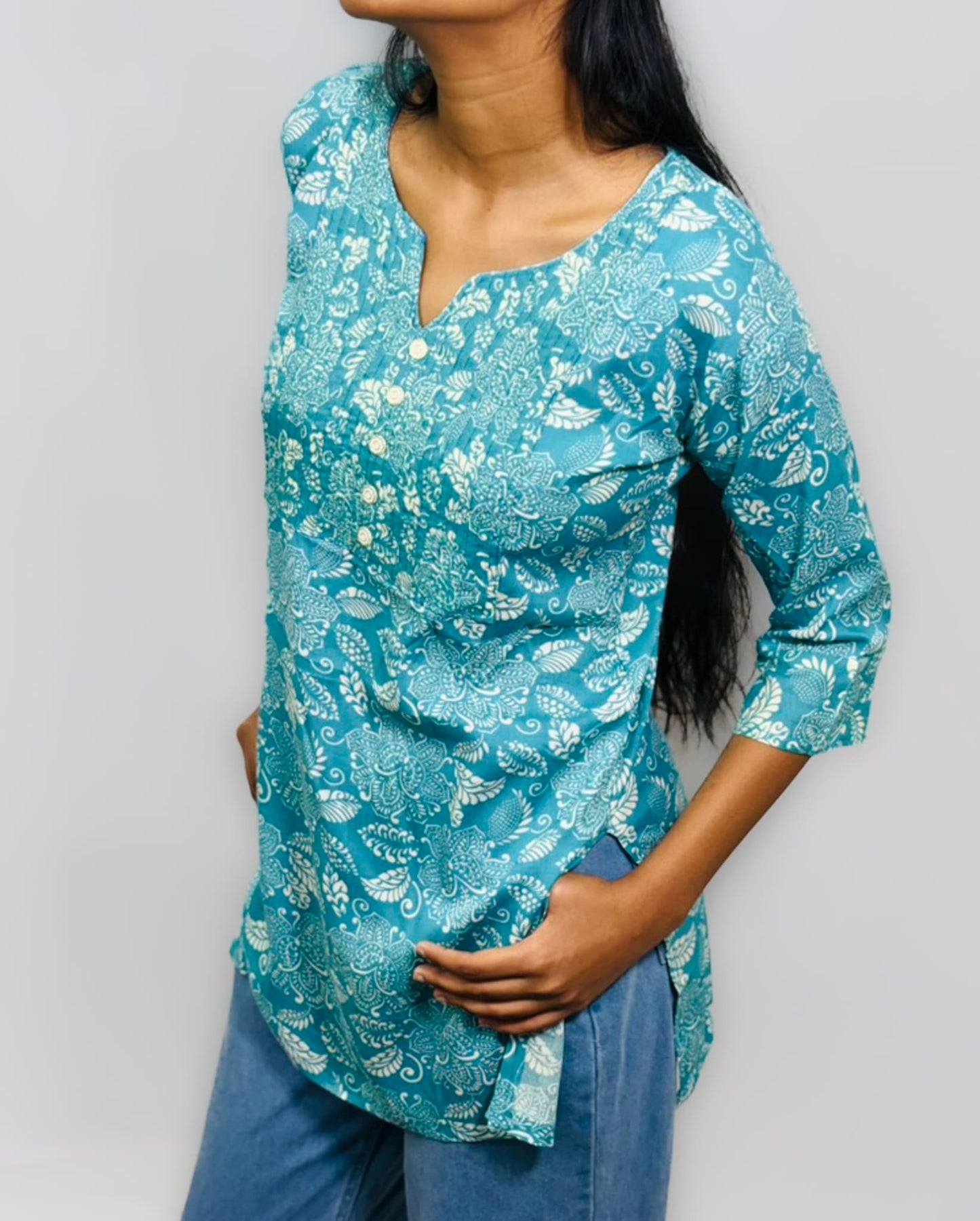 Woman wearing a turquoise floral blouse with a plain background