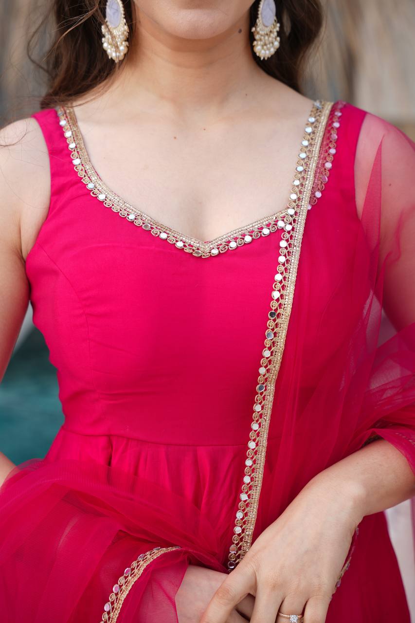 Close-up of a person wearing a bright pink traditional outfit with gold embroidery.
