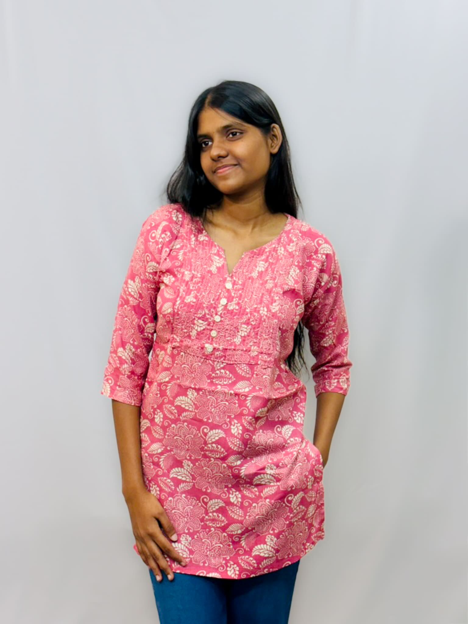 Woman wearing a pink floral dress against a plain background