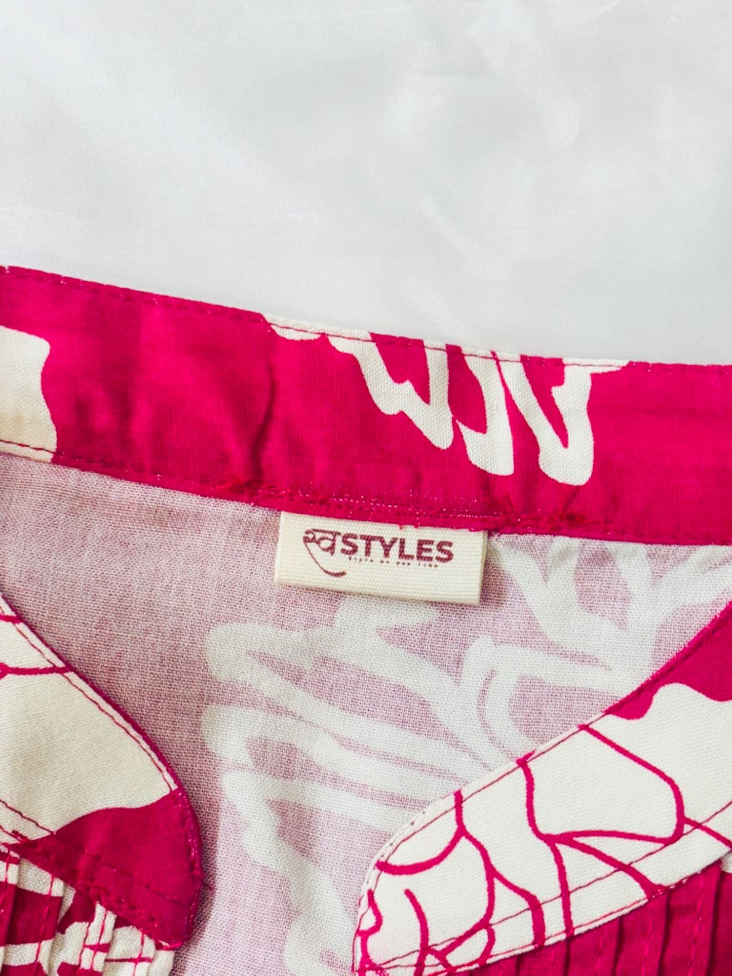 Close-up of a pink and white patterned fabric with a 'STYLES' label on a light gray background.