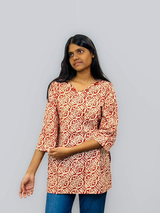 Woman wearing a red and white patterned top against a gray background