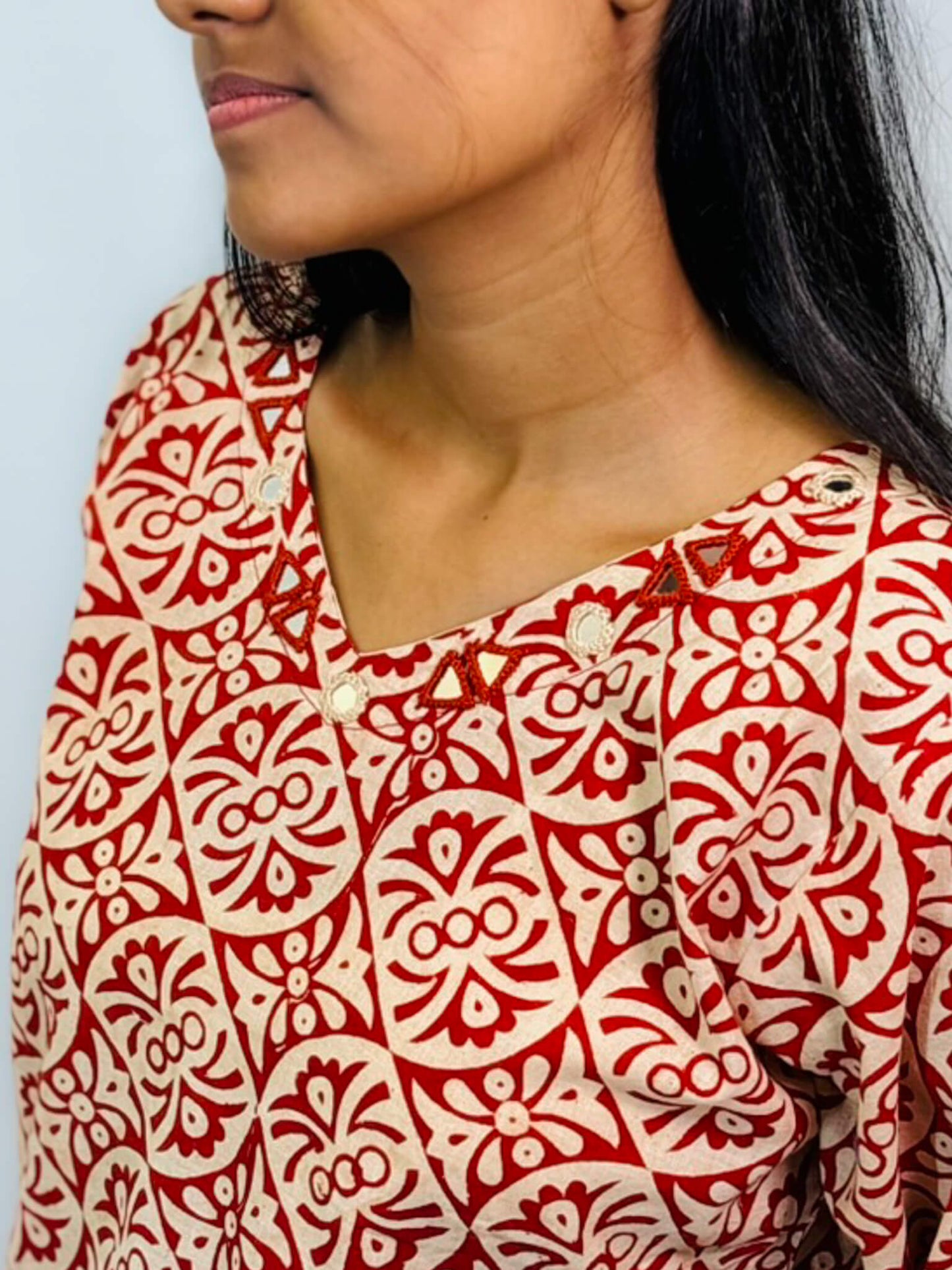 Red and white patterned shirt worn by a person against a light blue background