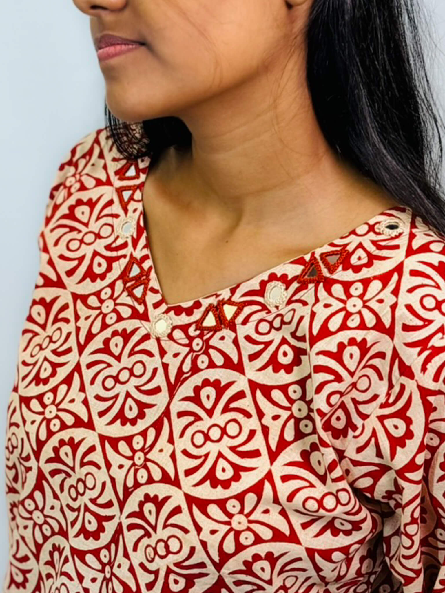 Red and white patterned shirt worn by a person against a light blue background