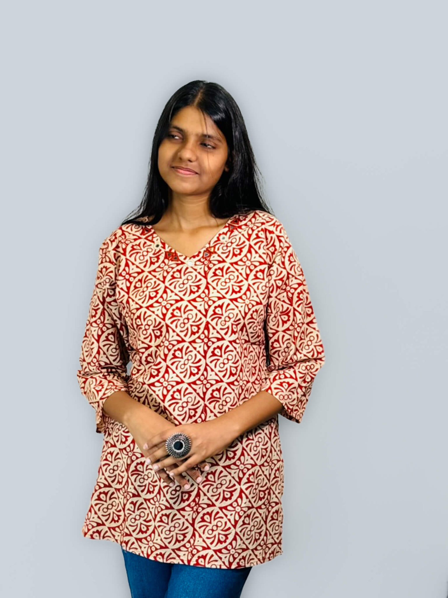 Woman wearing a red and white patterned top against a gray background