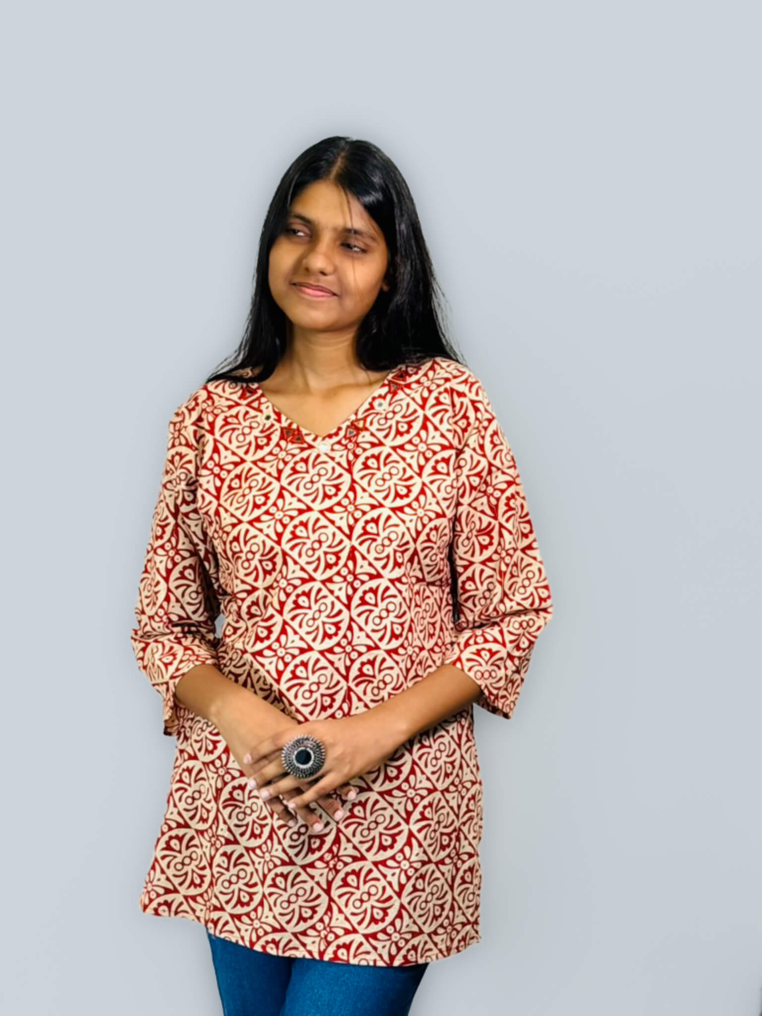 Woman wearing a red and white patterned top against a gray background