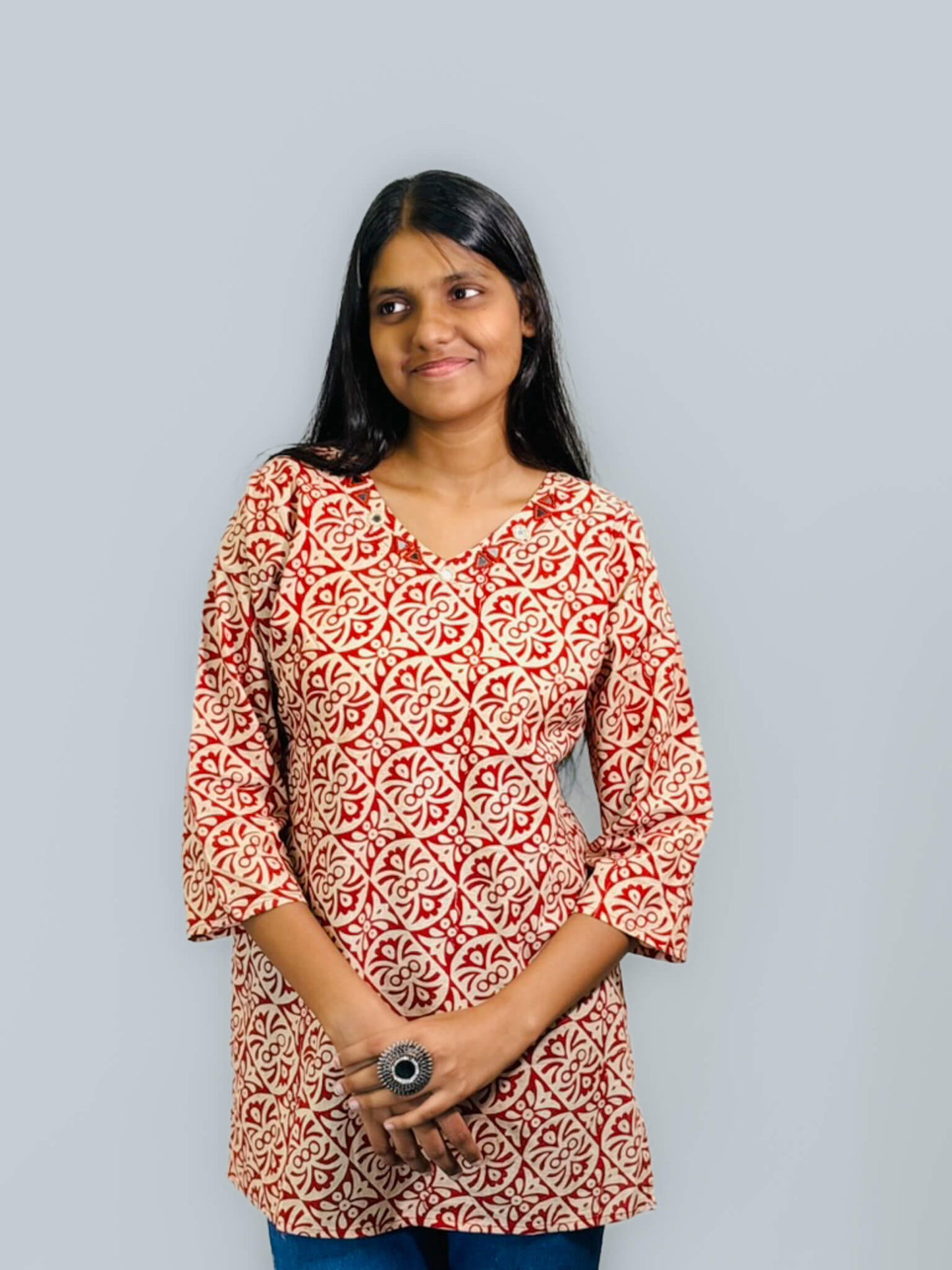 Woman wearing a red and white patterned kurta against a gray background