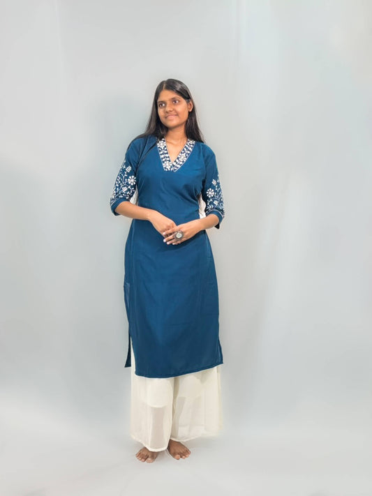 Woman wearing a blue kurta with white embroidery on a plain background
