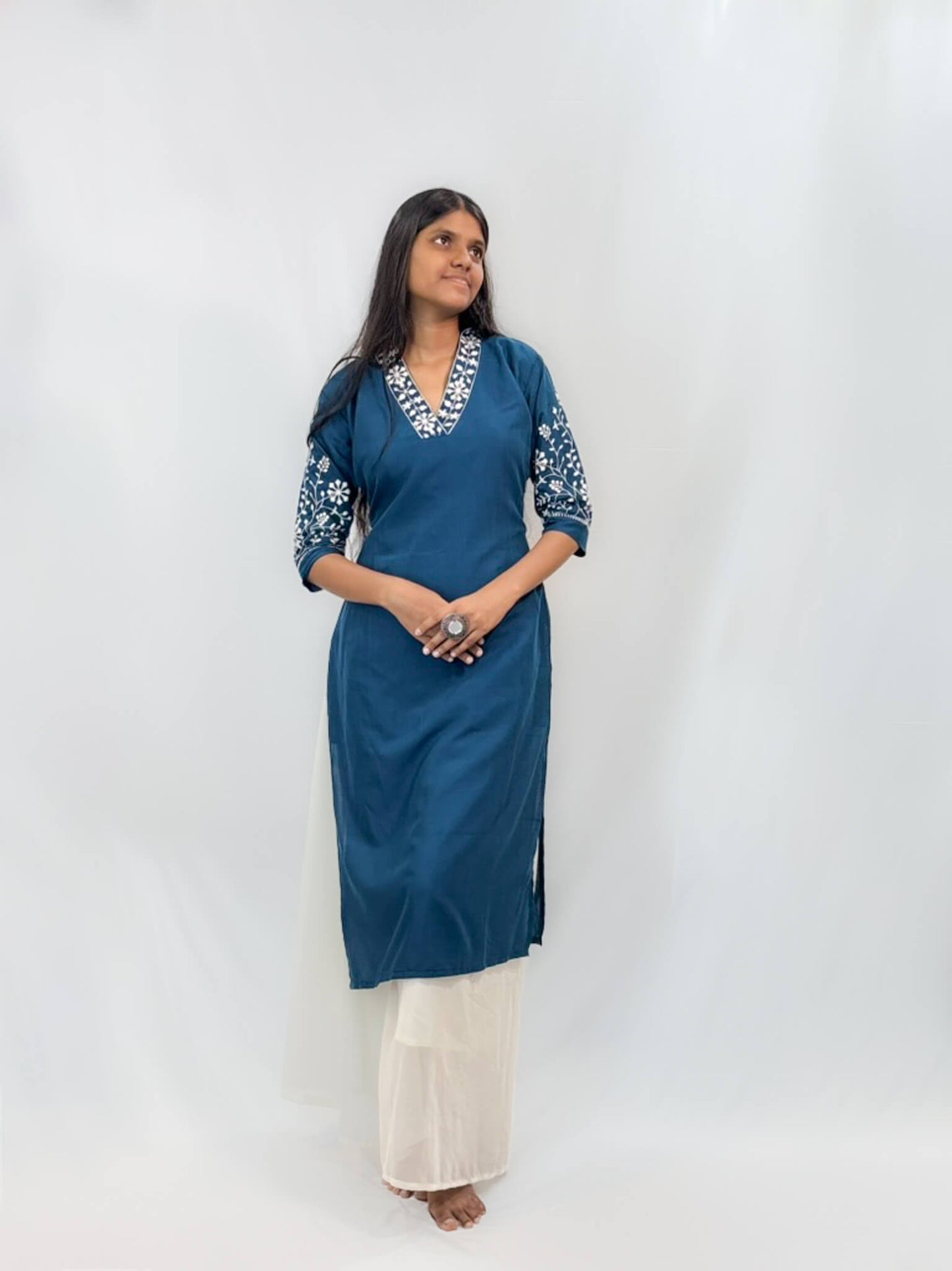 Woman wearing a blue kurta with white embroidery on a white background