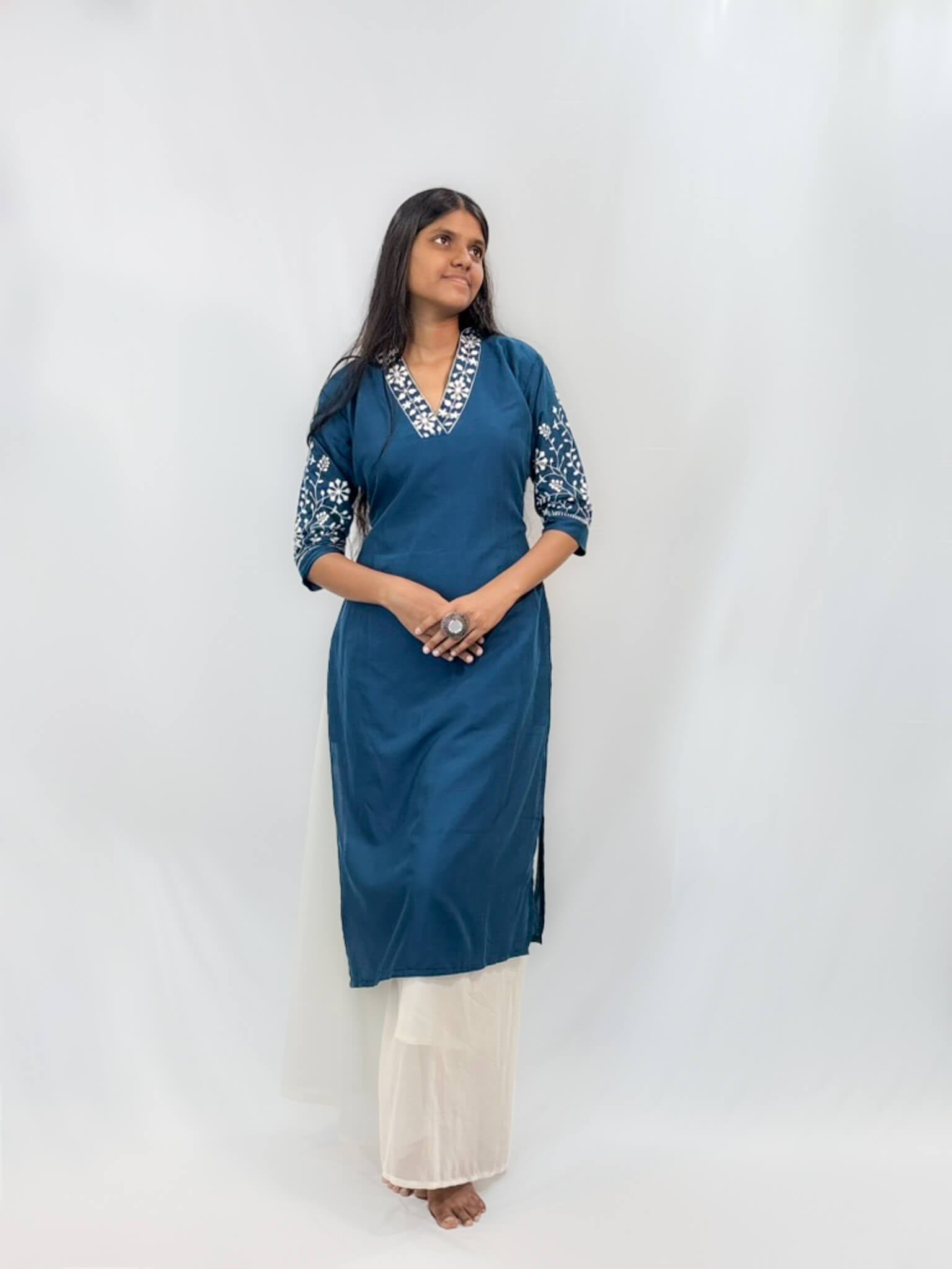 Woman wearing a blue kurta with white embroidery on a white background