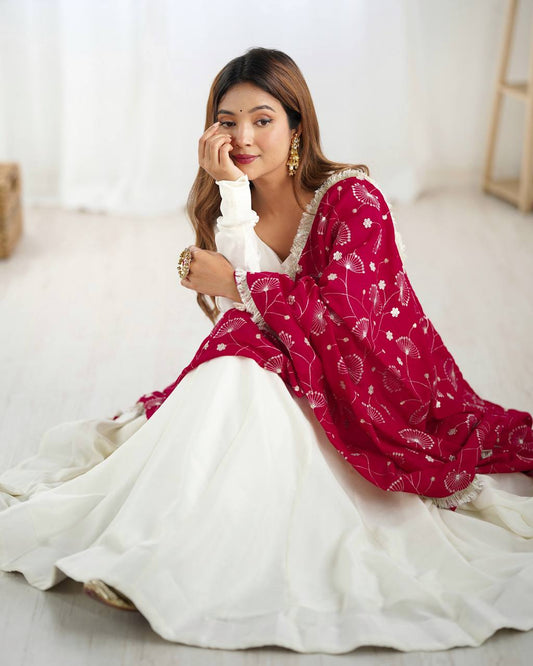 Woman in a red and white traditional outfit sitting on a light-colored floor.