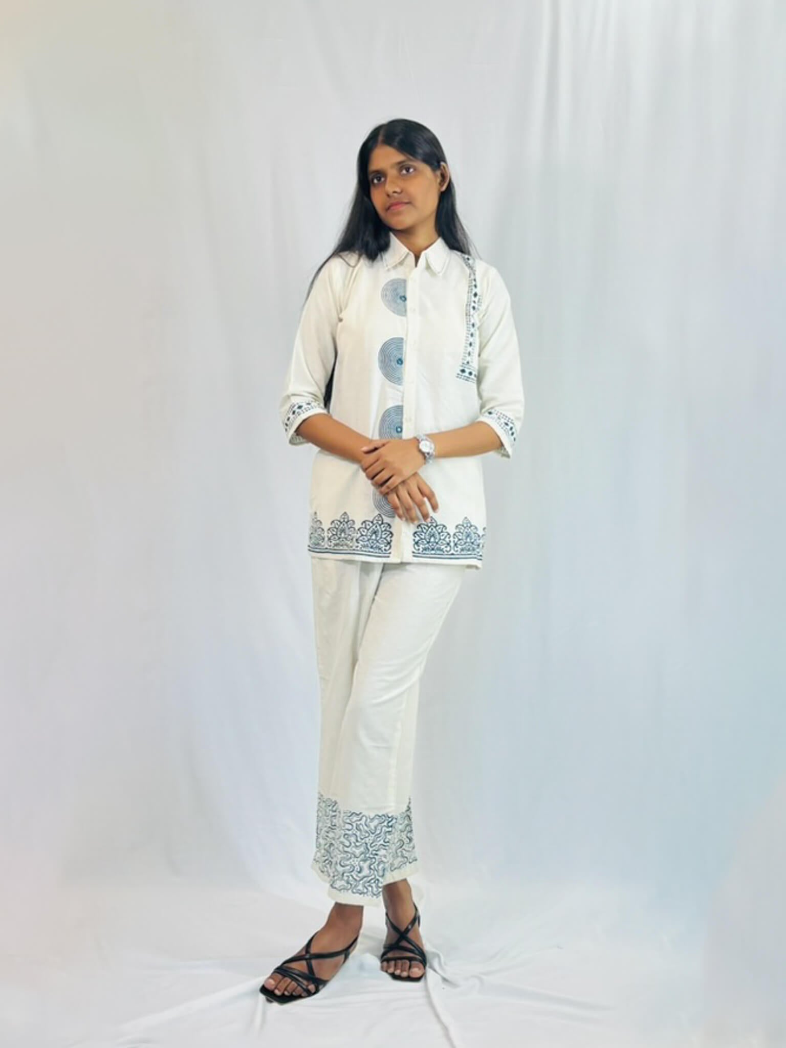 Person wearing a white outfit with blue patterns on a white background
