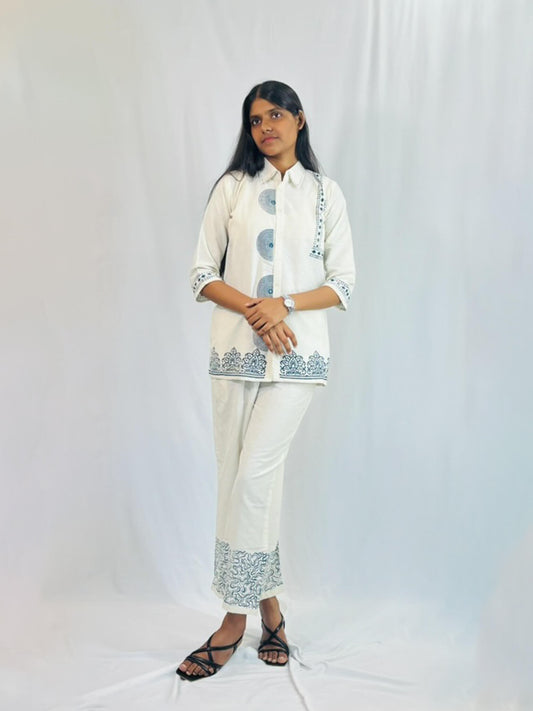 Person wearing a white outfit with blue patterns on a white background