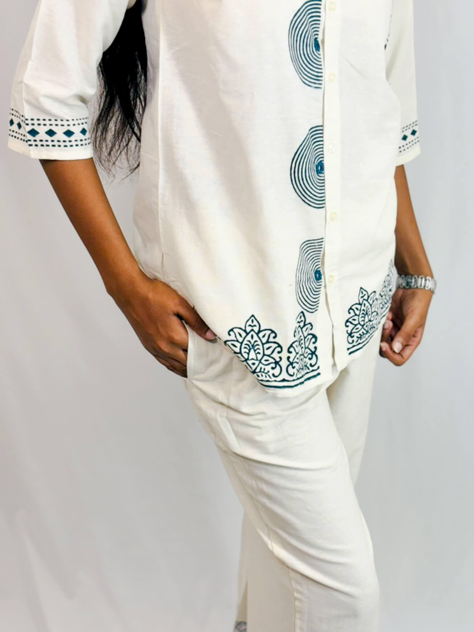 Person wearing a white outfit with green patterns on a plain background