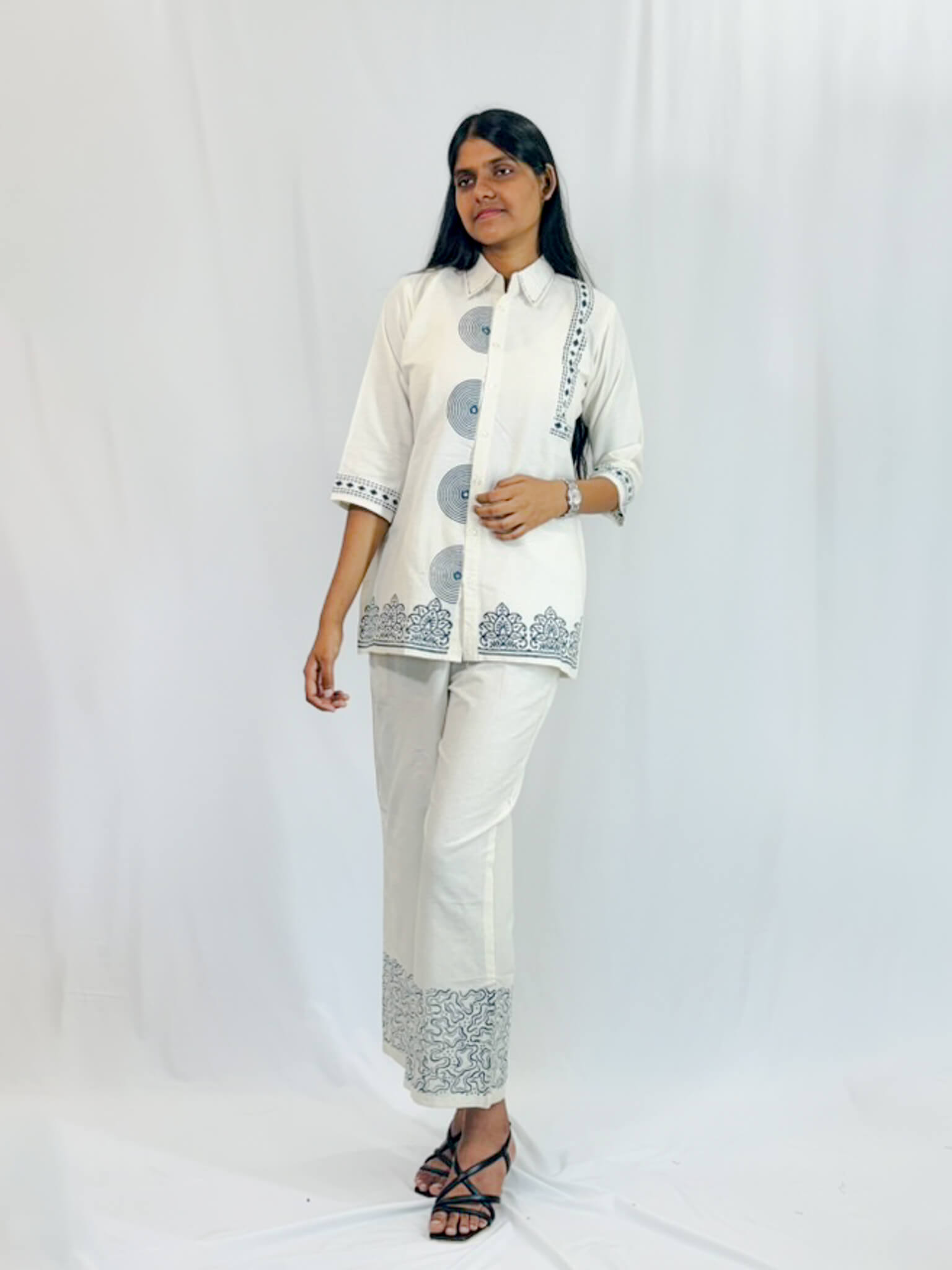 Woman wearing a white traditional outfit with black patterns on a white background