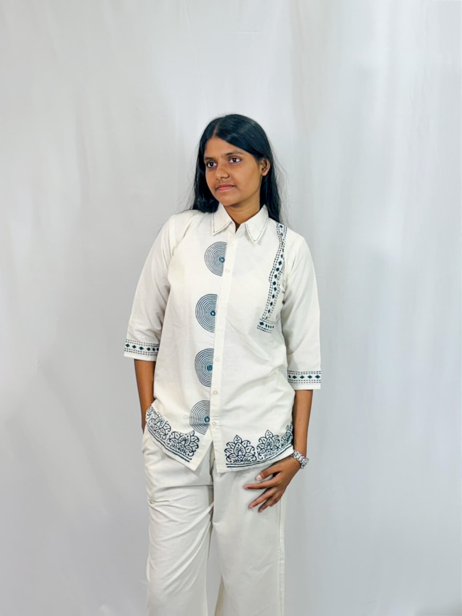 Woman wearing a white outfit with black patterns against a plain background