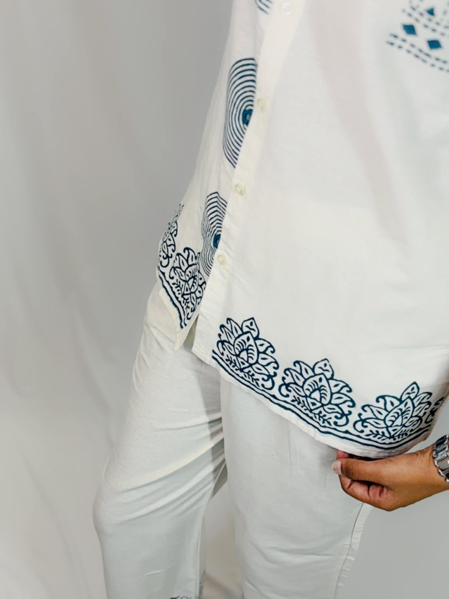 White fabric with blue embroidery held by a hand against a white background