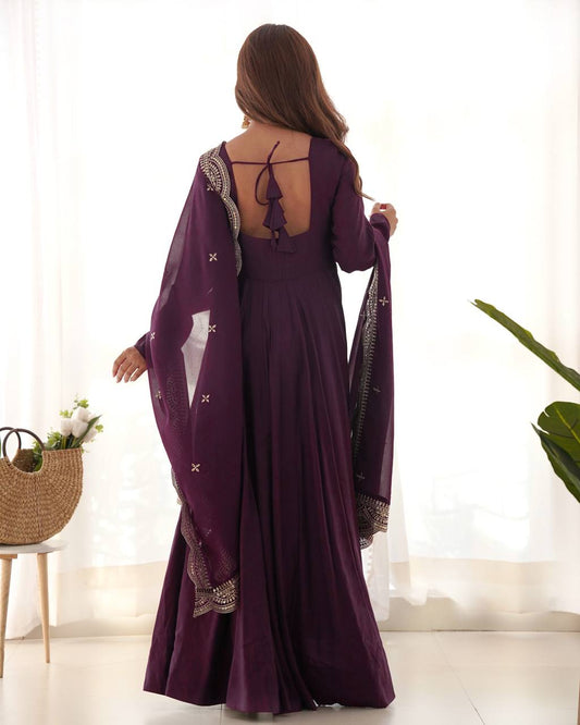Woman wearing a purple dress with a matching shawl in a bright room.