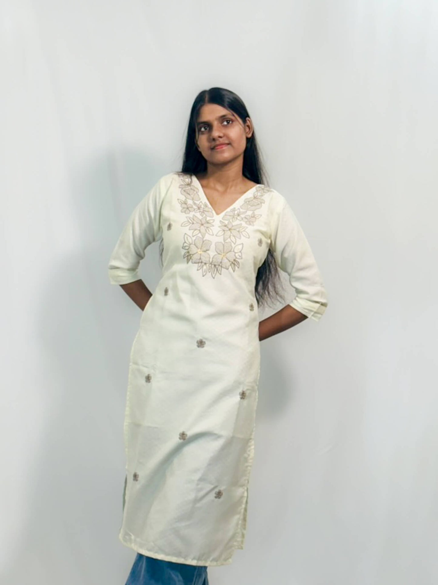 Woman wearing a white embroidered kurta against a plain background