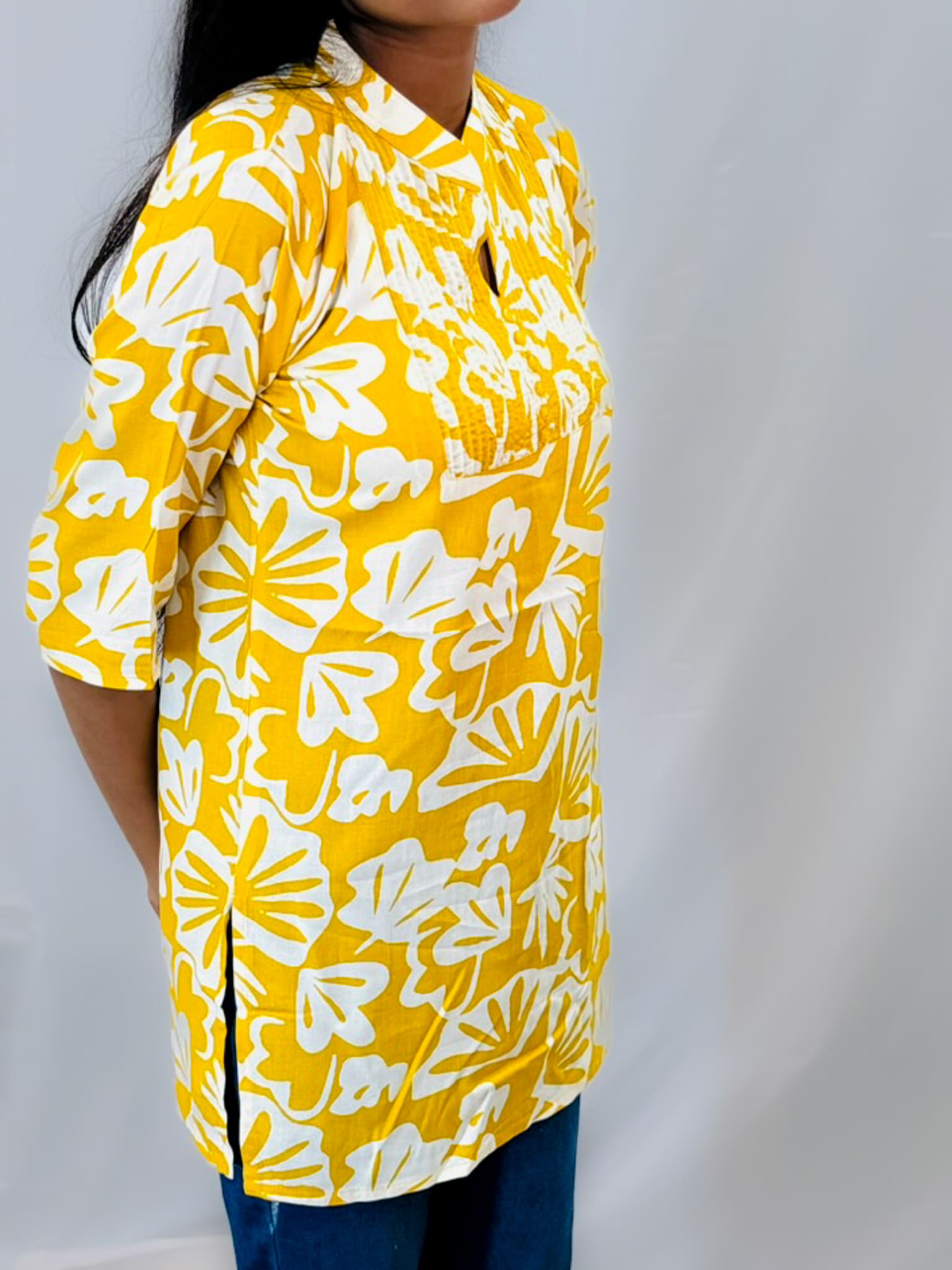 Yellow floral patterned shirt worn by a person on a plain background